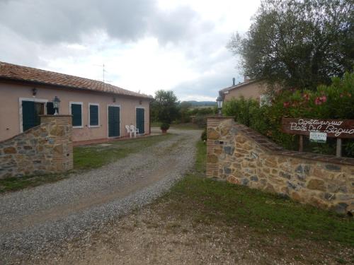 a dirt road next to a building with a stone wall at Piane Del Bagno in Saturnia