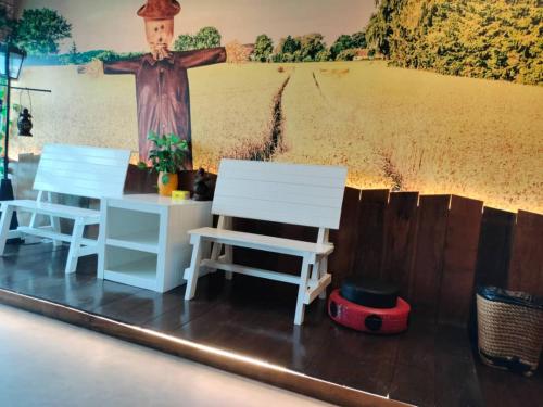two white chairs and a table in front of a wall at Sekinchan PaddyCruise Homestay Wifi in Sekincan