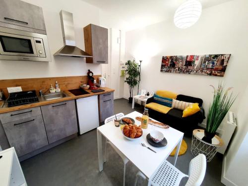 una cucina e un soggiorno con tavolo e divano di Le binic - proche gare et centre a Saint-Brieuc