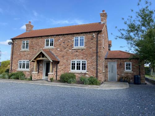 a brick house with a driveway in front of it at Foxglove in Thimbleby