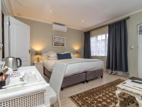 a bedroom with a bed and a desk and a sink at Whale Rock Luxury Lodge in Hermanus