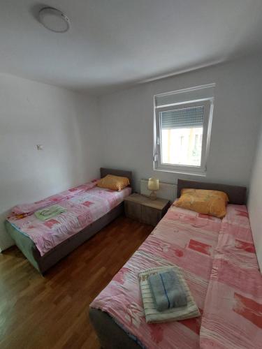 two beds in a room with a window at Sobe za izdavanje Nedeljković in Lukovo