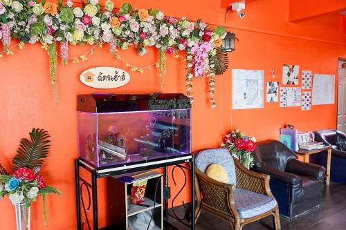 a room with a fish tank and flowers on the wall at Chat House Chiang Rai in Chiang Rai