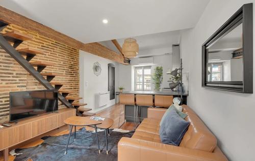 a living room with a brown couch and a brick wall at Les Relais du Capitole - Appartements d'hôtes in Toulouse
