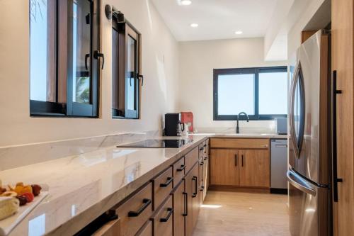 圣何塞德尔卡沃Amazing Beachfront Casa Del Mar Penthouse的厨房配有木制橱柜和不锈钢冰箱