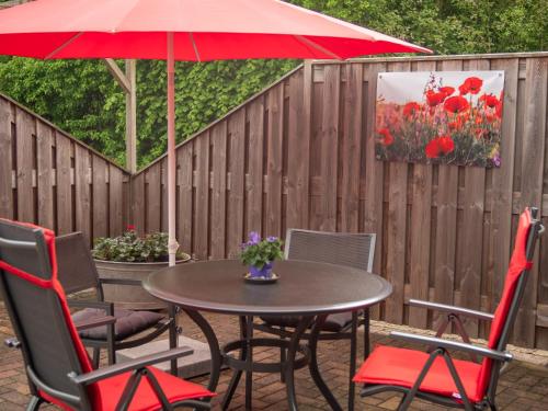 a table and chairs with a red umbrella on a patio at Vakantiehuisjes "De Veldzijde" in Losser