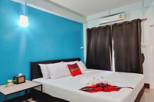 a bedroom with a white bed with a blue wall at Chat House Chiang Rai in Chiang Rai
