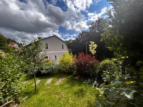 a white house in the middle of a garden at Apartmány u Kuželky in Loket