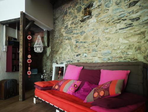 a couch in a room with a stone wall at Une chambre au jardin in Saint-Pons-de-Thomières