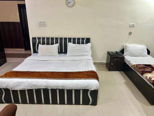 a bedroom with two beds and a clock on the wall at Hotel Dev Palace, Badrinath road, Tapovan- Rishikesh in Badrīnāth