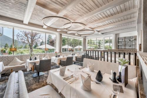 a restaurant with white tables and chairs and large windows at Natur & Spa Hotel Lärchenhof in Seefeld in Tirol