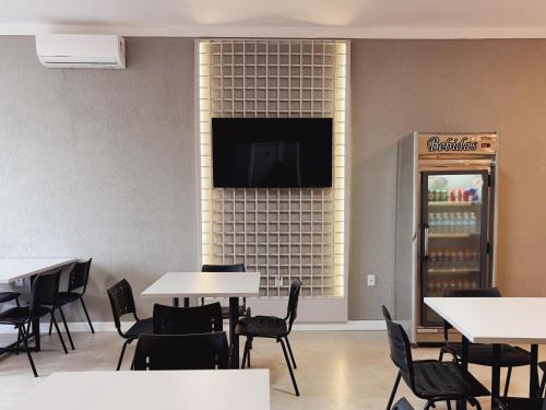 un restaurant avec des tables et des chaises et une télévision murale dans l'établissement Hotel Corporativo Paragominas, à Paragominas
