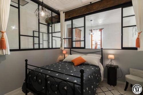a bedroom with a black bed and some windows at Escapade lauragaise in Saint-Félix-Lauragais