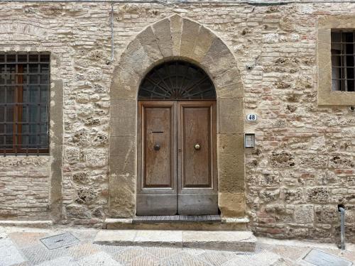 a wooden door in a stone building at Tuscany Saloon - Historical centre in Colle Val D'Elsa