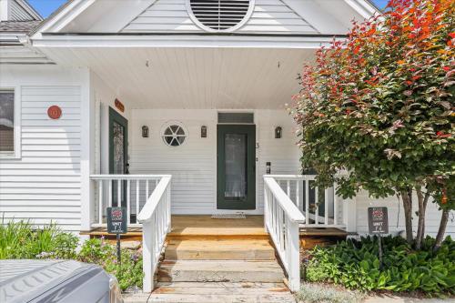 a front porch of a white house with a green door at Riverside Getaway in Stowe