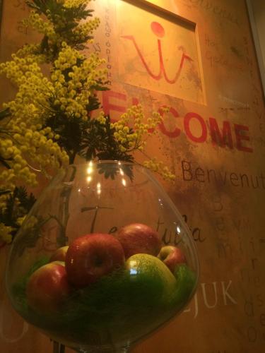 a glass vase filled with apples and flowers on a table at Hotel Aspromonte in Milan