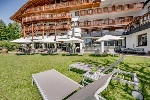 a hotel with chairs and umbrellas in front of a building at Natur & Spa Hotel Lärchenhof in Seefeld in Tirol