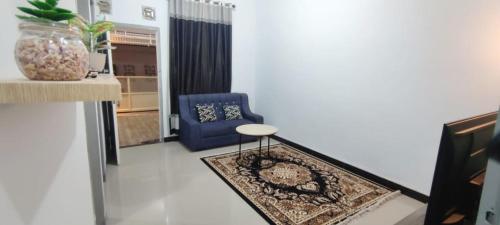 a living room with a blue chair and a rug at Naya Homestay Kuningan in Balong