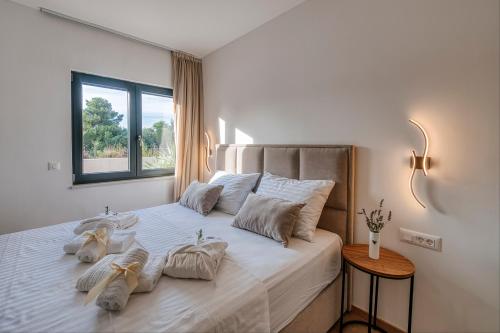 Un dormitorio con una cama blanca con almohadas y una ventana. en Villa Relax Petrčane, en Petrčane