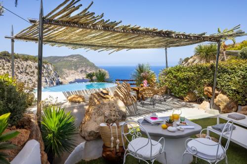 a patio with a table and chairs and a view of the ocean at Hacienda Na Xamena, Ibiza in Na Xamena