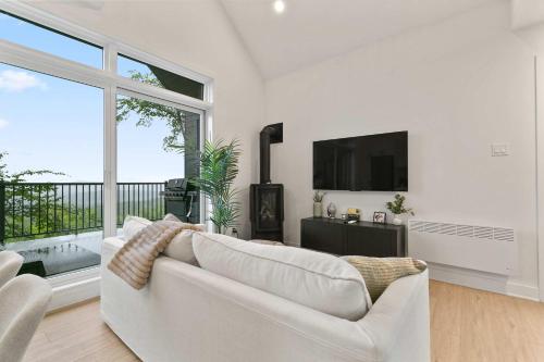 a living room with a white couch and a large window at Elska - SPA and Mountain in Saint Come