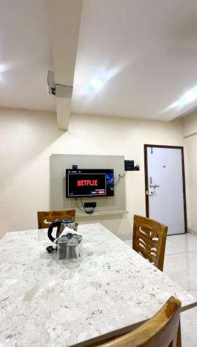 a room with a table and a tv on the wall at Sapphire Service Apartment in Navi Mumbai