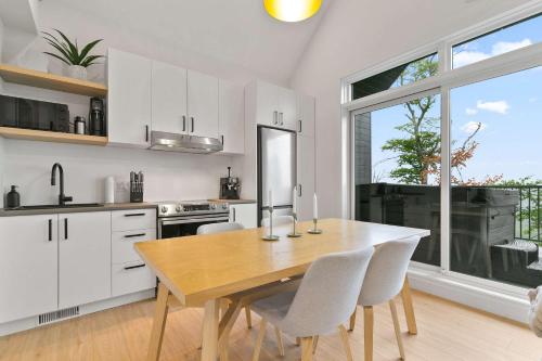a kitchen with a wooden table and white cabinets at Elska - SPA and Mountain in Saint Come