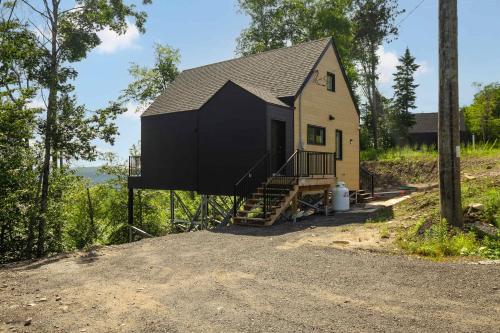 a tiny house with a black roof on a hill at Elska - SPA and Mountain in Saint Come