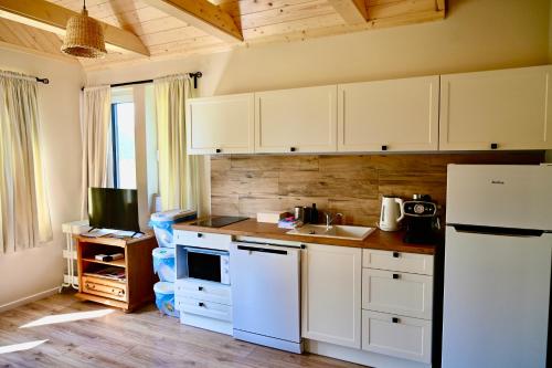 a kitchen with white cabinets and a white refrigerator at Żubrowe Sioło - dom w naturze - najładniejsze widoki - nowość in Białowieża