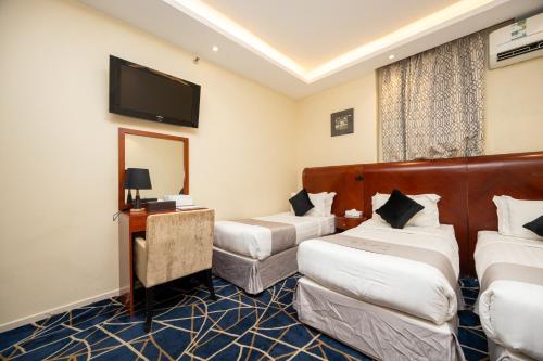 a hotel room with two beds and a flat screen tv at Al Manara Ewaa Hotel in Mecca