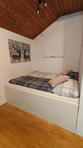 a bed in a white room with two pictures on the wall at Wochenend Ferienhaus mit tollen Ausblick in die Bucklige Welt in Kühbach
