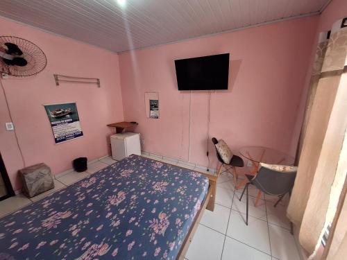 a room with a bed and a flat screen tv at Quartos da lagoa in Cabo Frio