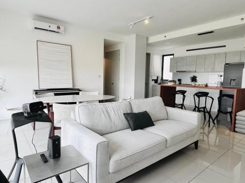 a living room with a white couch and a kitchen at NEW Designer Condo - Panoramic Forest View - Steps To IOI City Mall - Your Best Urban Retreat in Putrajaya