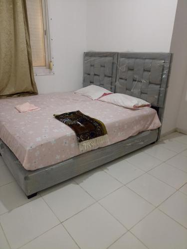 a bed sitting in a bedroom with a tiled floor at Bel appart à saidia in Saidia 