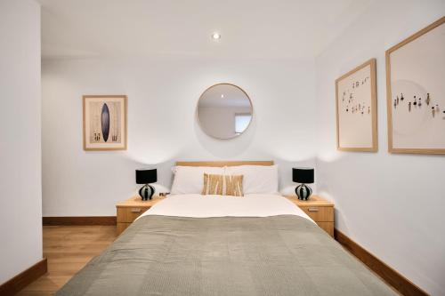 - une chambre avec un lit avec un miroir et deux lampes dans l'établissement Harbour Heights - Escape Ordinary, à Portstewart