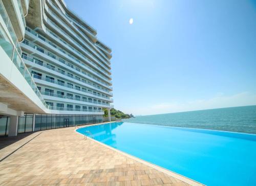 a large building with a swimming pool next to the ocean at Bamboo beach tsikhisdziri in Tsikhisdziri
