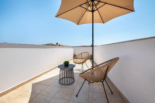 a patio with two chairs and a table and an umbrella at United Cretan Villas in Agia Marina Nea Kydonias