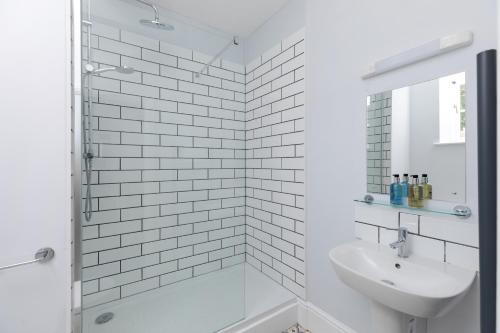 a white bathroom with a shower and a sink at The Hunters Inn in Martinhoe