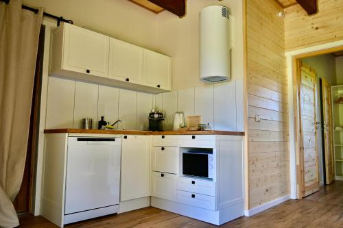 a kitchen with white cabinets and a stove at Żubrowe Sioło - dom w naturze - najładniejsze widoki - nowość in Białowieża