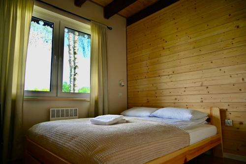 a bedroom with a bed with a wooden wall and two windows at Żubrowe Sioło - dom w naturze - najładniejsze widoki - nowość in Białowieża