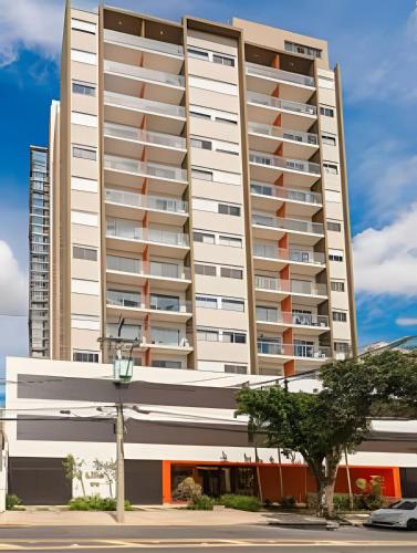 a tall white building with a tree in front of it at Aconchegante Studio no Cambuí in Campinas