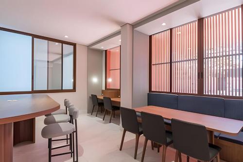 a dining room with tables and chairs and windows at Aconchegante Studio no Cambuí in Campinas