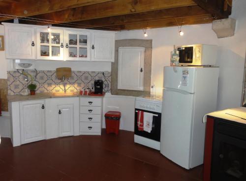 a kitchen with white cabinets and a white refrigerator at Herdade do moinho in Santiago do Cacém