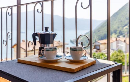 a table with two cups and a coffee maker on it at IseoLakeRental - Fuori Porta in Tavernola Bergamasca