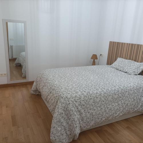 a white bedroom with a bed and a mirror at Apartamento Rym in Siero