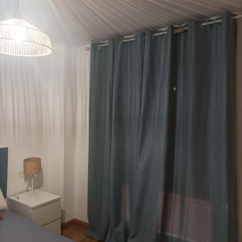 a bedroom with blue curtains and a bed and a lamp at Apartamento Rym in Siero