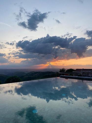 a large swimming pool with a sunset in the background at Villa Belvedere Langhe in Belvedere Langhe