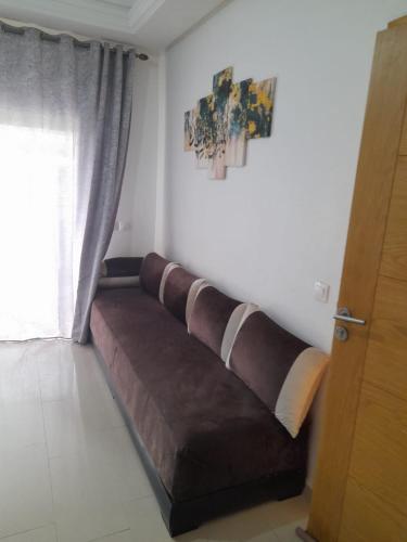 a brown couch in a room with a window at La cascade 2 in Sidi Rahal