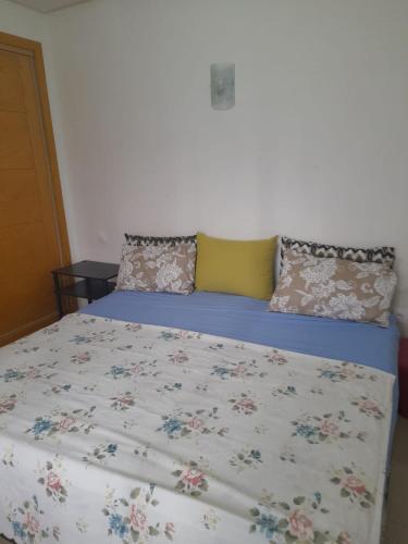 a bed with a floral bedspread and pillows on it at La cascade 2 in Sidi Rahal