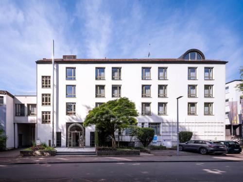 a white building with a tree in front of it at Christkönigshaus in Stuttgart